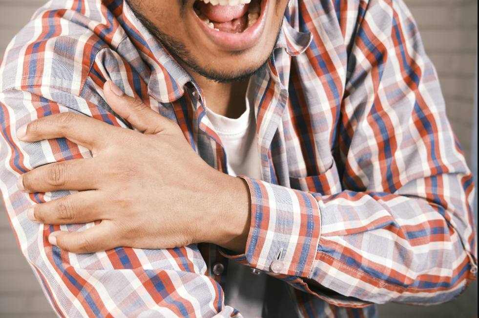 Hombre con gesto de dolor sujetándose el hombro izquierdo con la mano